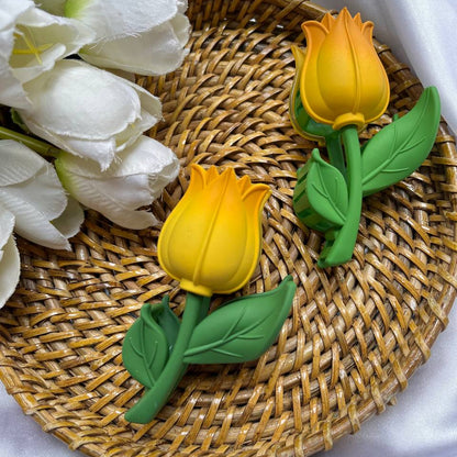 Two yellow tulip-shaped objects on a woven mat with white flowers.