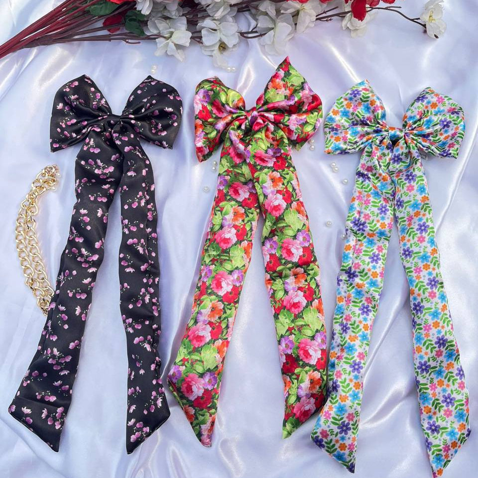 Three floral hair ribbons on a white fabric background with red flowers.