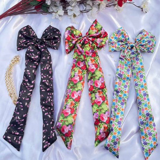 Three floral hair ribbons on a white fabric background with red flowers.